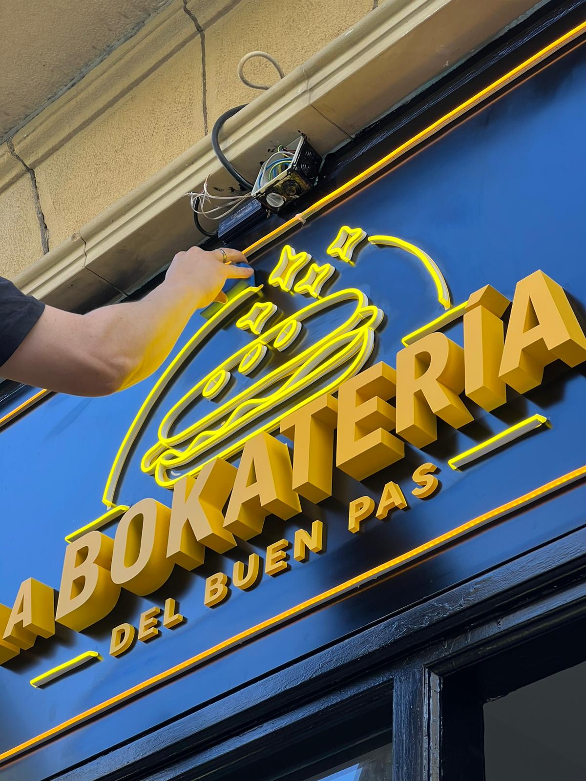 Rótulo La Bokatería — letras corpóreas doradas con neón